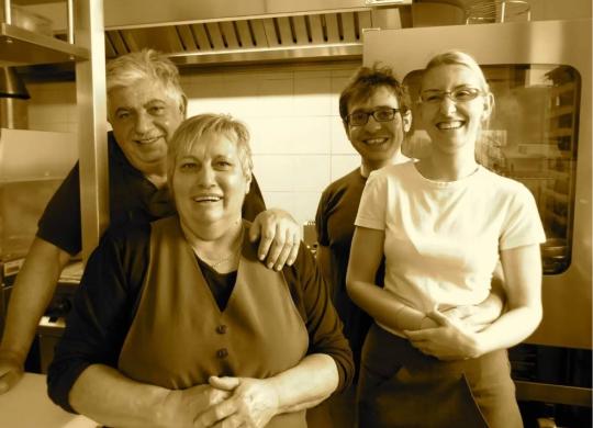 Gruppo di persone sorridenti in una cucina, probabilmente uno staff di ristorante.