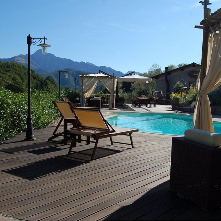 Piscina all'aperto con lettini, gazebo e vista sulle montagne.