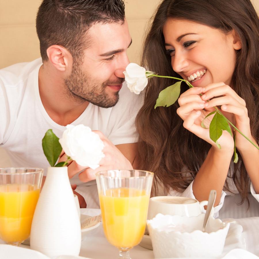 Coppia felice a colazione con fiori e succo d'arancia.